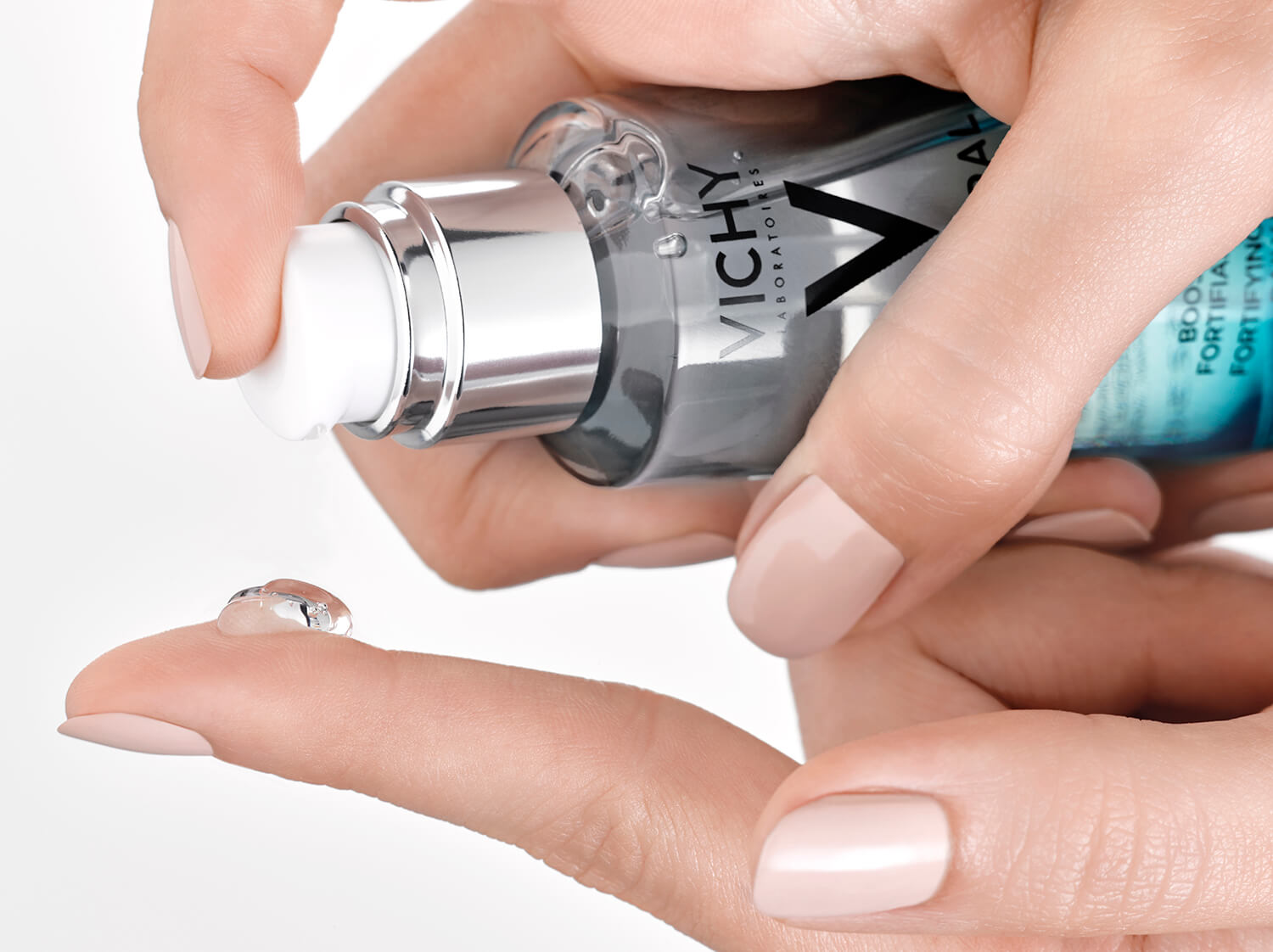 Hand hält ein Serum von Vichy und gibt einen Tropfen davon zur Anwendung auf den Finger 