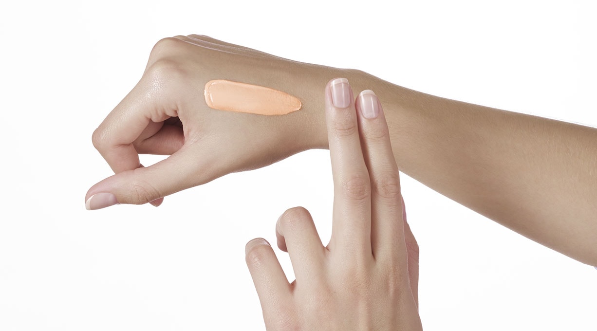Une crème est appliquée avec deux doigts sur la main droite.