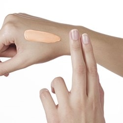 Une crème est appliquée avec deux doigts sur la main droite.