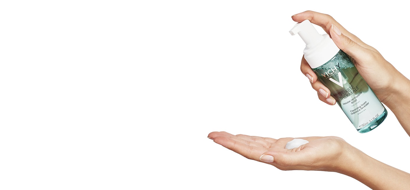 Eine Hand trägt den PURETÉ THERMALE Reinigungsschaum von Vichy auf die Haut auf.