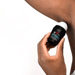 Hand verteilt das Vichy HOMME 72h Anti-Flecken Invisible Deo in der Achsel eines Mannes