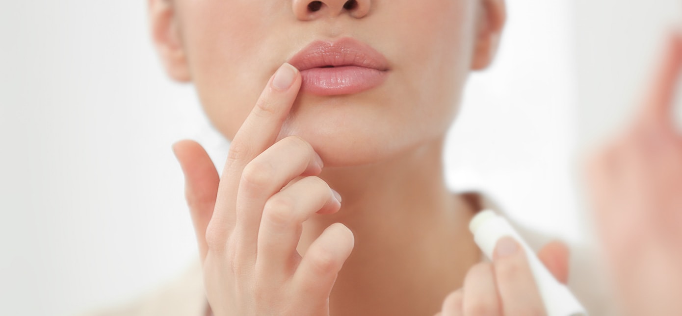 Untere Gesichtspartie einer Frau mit glatter Haut, die mit dem Zeigefinger ihren Mundwinkel berührt