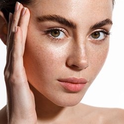 Visage d'une jeune femme avec la main levée sur le côté de son visage.