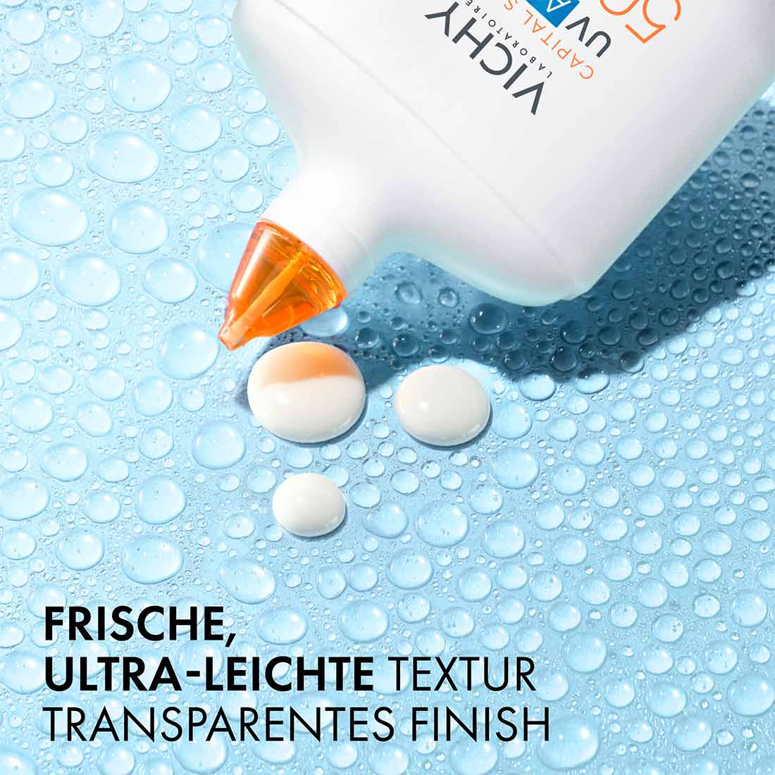 Ein paar Tropfen des Capital Soleil UV Aqua Hydrating Invisible Fluid auf einem blauen Hintergrund. Das Capital Soleil UV Aqua Hydrating Invisible Fluid hat eine frische, ultra-leichte Textur und ein transparentes Finish.