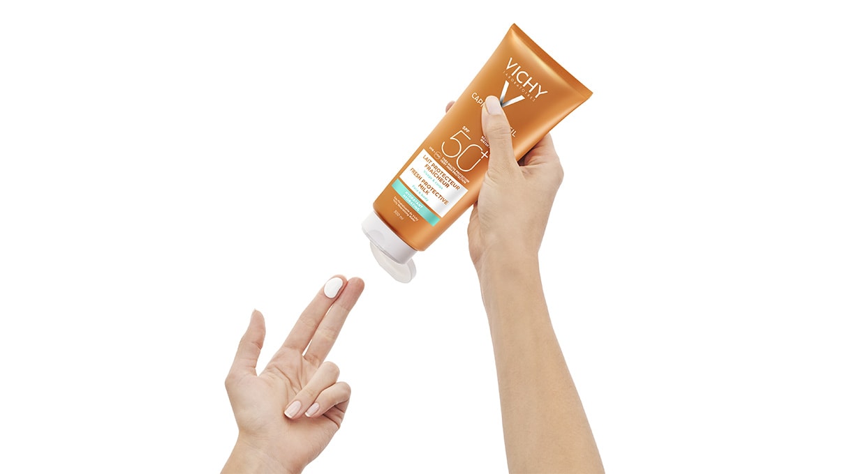 Eine Hand entnimmt eine kleine Menge Sonnencreme aus der CAPITAL SOLEIL Familienmilch von Vichy