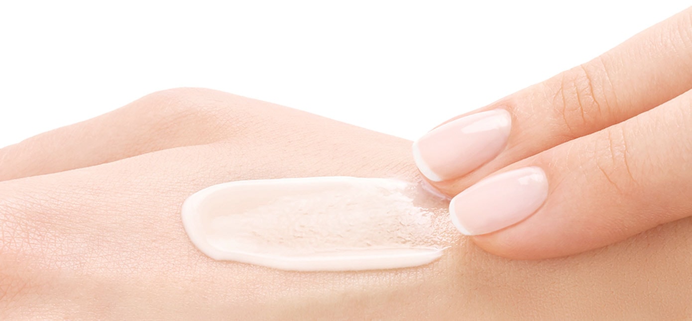 Zwei Finger verstreichen eine Creme auf der Haut