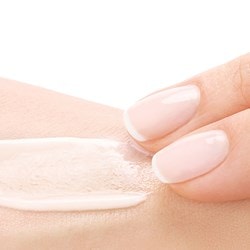 Zwei Finger verstreichen eine Creme auf der Haut